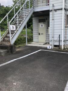 a parking lot in front of a building with a white door at Chichibu Mizuno-stay 水野ステイ最大６名様 in Chichibu