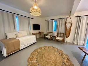 a bedroom with a bed and a table and a tv at Pousada Caraíva in Caraíva