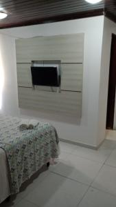 Habitación con cama y TV en la pared. en Pousada Beira Litoral, en João Pessoa