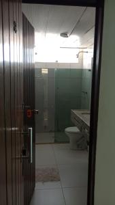 puerta a un baño con aseo y espejo en Pousada Beira Litoral, en João Pessoa