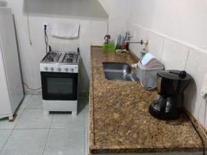 a small kitchen with a stove and a sink at Recanto do Parque in Campo Grande
