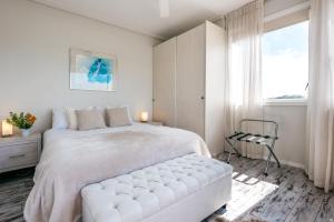 a white bedroom with a large bed and a window at Oneroa Central - Coast & Country in Oneroa