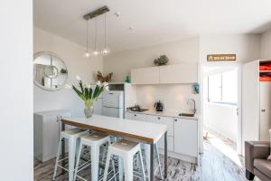 a kitchen with white cabinets and a table and stools at Oneroa Central - Coast & Country in Oneroa