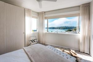 Dormitorio con ventana grande con vistas al agua en Oneroa Central - Coast & Country, en Oneroa