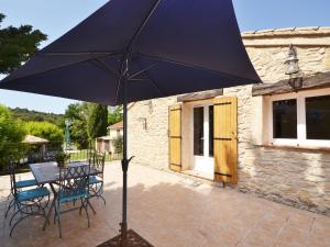 een tafel en stoelen met een parasol op een patio bij Flat with private pool in the heart of nature in Malaucène