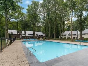 een zwembad in een resort met bomen en gebouwen bij Snug apartment in Houthalen Oost with heated pool in Drijhoeven