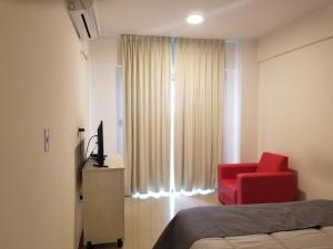 1 dormitorio con silla roja y ventana en DELFINA suites 1A en La Rioja