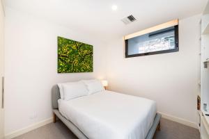 Un pequeño dormitorio con una cama blanca y una ventana en Accommodate Canberra - Canberra 22, en Kingston 