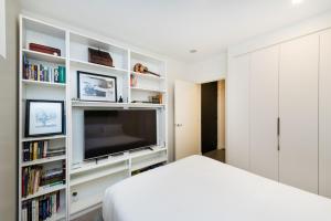 a white bedroom with a television and book shelves at Accommodate Canberra - Canberra 22 in Kingston 