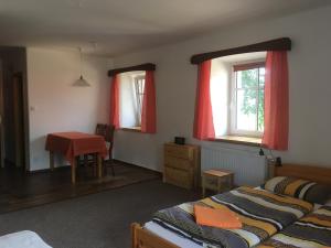 a bedroom with a bed and a table and two windows at Ubytování v Ouklidu in Nedrahovice