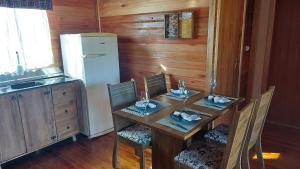 a kitchen with a table with chairs and a refrigerator at Cabana Entre Lagos in São Joaquim
