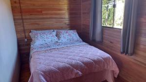1 dormitorio con 1 cama en una pared de madera en Cabana Entre Lagos en São Joaquim