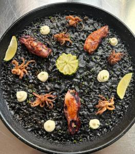 a black plate of food with seafood on it at Pension Amarantos in Suances