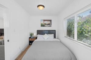 a white bedroom with a bed and a window at ALKI Retreat! Steps-2-BEACH - PARKING in Seattle