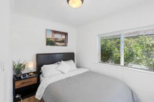 a white bedroom with a bed and a window at ALKI Retreat! Steps-2-BEACH - PARKING in Seattle