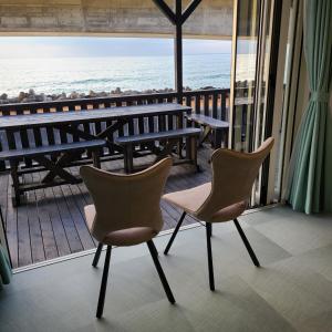 2 stoelen en een tafel op een balkon met uitzicht op het strand bij Fluctus - Vacation STAY 16974v in Hitachi
