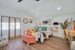 a bedroom with a bed with colorful pillows and a chair at Sweet Nest Bluffton Cottage in Bluffton