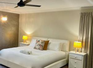 een slaapkamer met een wit bed en 2 lampen bij LAHOOL GUEST HOUSE JUST A CREEKSIDE STROLL TO TOWN in Stanthorpe