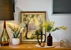 een schilderij op een tafel met wat vazen erop bij LAHOOL GUEST HOUSE JUST A CREEKSIDE STROLL TO TOWN in Stanthorpe