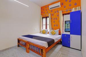 1 dormitorio con 1 cama con pared azul y naranja en OYO Hotel Munroe Homestay, en Kollam