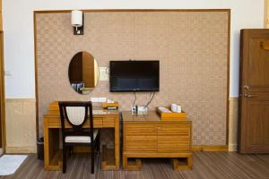 een bureau met een televisie aan de muur bij Dragon Manor Resort in Renai