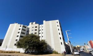 ein hohes weißes Gebäude mit einem Baum davor in der Unterkunft TIERRA Alojamientos in Salta