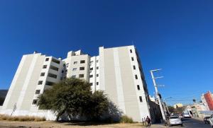 a tall white building with a tree in front of it at TIERRA Alojamientos in Salta