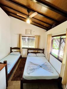 two beds in a room with two windows at Chales de Arraial d' Ajuda in Arraial d'Ajuda