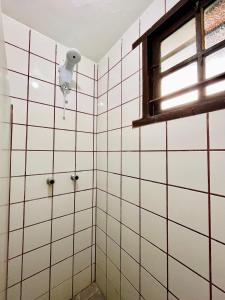 a bathroom with white tiled walls and a window at Chales de Arraial d' Ajuda in Arraial d'Ajuda