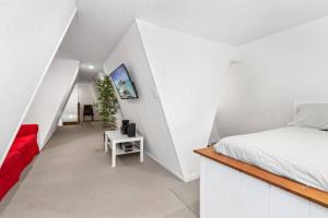 a white bedroom with a bed and a red couch at The Pod in Peregian Beach