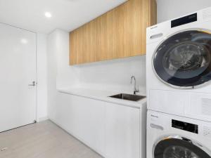 a white laundry room with a washer and dryer at Luxury with lake and hinterland views in Noosa Heads