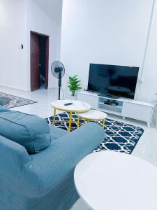 een woonkamer met een blauwe bank en een tv bij Iman Homestay Temerloh in Temerloh