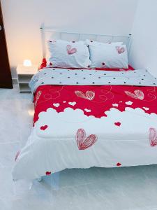 - un lit doté d'un couvre-lit rouge et blanc avec le cœur dans l'établissement Iman Homestay Temerloh, à Temerloh