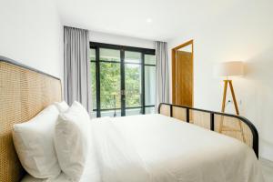 Una cama blanca con almohadas blancas y una ventana. en Umalas Living Villa, en Canggu 53 fotos más