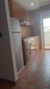 a kitchen with a white refrigerator and a tile floor at Prachtige appartement in heel rustige omgeving in Chozas