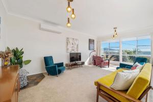 a living room with a couch and chairs and a tv at Retro Beach House in Crescent Head