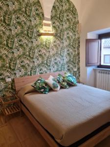 uma cama com almofadas num quarto com uma parede em Dimora degli angeli em LʼAquila
