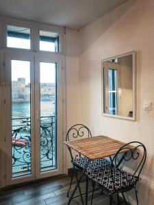 a table and chairs in a room with a balcony at Résidence Collioure Plage in Collioure