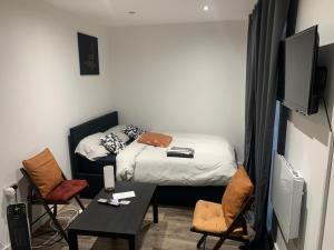 ein kleines Zimmer mit einem Bett, einem Tisch und Stühlen in der Unterkunft Cosy B1 Studio Apartment in London