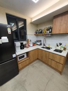 a kitchen with a black refrigerator and wooden cabinets at Hao Guesthouse in Hongdae in Seoul