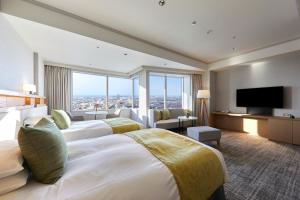 a hotel room with two beds and a flat screen tv at Hotel Nikko Kanazawa in Kanazawa