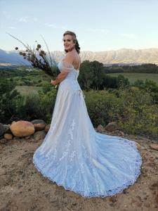 a woman in a wedding dress holding a bouquet at Riviera Cottage in Tulbagh