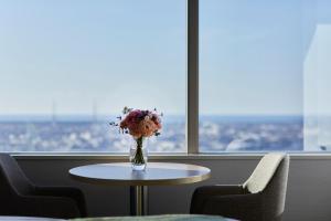 a vase of flowers on a table in front of a window at Hotel Nikko Kanazawa in Kanazawa