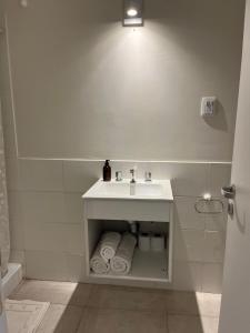 a white bathroom with a sink and towels at Departamento con Vista a los cerros con Asador in Yerba Buena