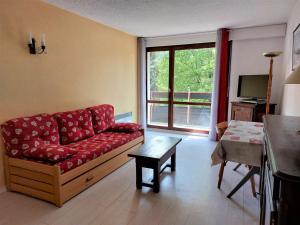 a living room with a red couch and a table at Appartement cosy à Autrans, 6 pers, 54m², balcon, proche pistes et commerces - FR-1-737-49 in Autrans