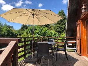 ein Tisch und Stühle mit einem Sonnenschirm auf einem Deck in der Unterkunft Chalet cosy avec terrasse exposée sud - 2km du centre, 2 chambres, 4 pers, parking privé. - FR-1-737-52 in Autrans + 3 Fotos