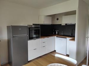 cocina con armarios blancos y nevera de acero inoxidable en Appartement Autrans-Méaudre en Vercors-Autrans, 2 pièces, 4 personnes - FR-1-737-7 en Autrans