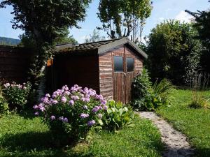 una pequeña casa de perros de madera en un jardín con flores en Maison Autrans-Méaudre en Vercors-Autrans, 3 pièces, 4 personnes - FR-1-737-41 en Autrans