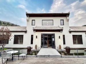 un edificio blanco con sillas y mesas delante de él en Vangen Hotel, en Miyun