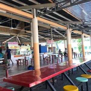 a red bench in a building with tables and chairs at Bintan Service Apartment in Sebungsungai